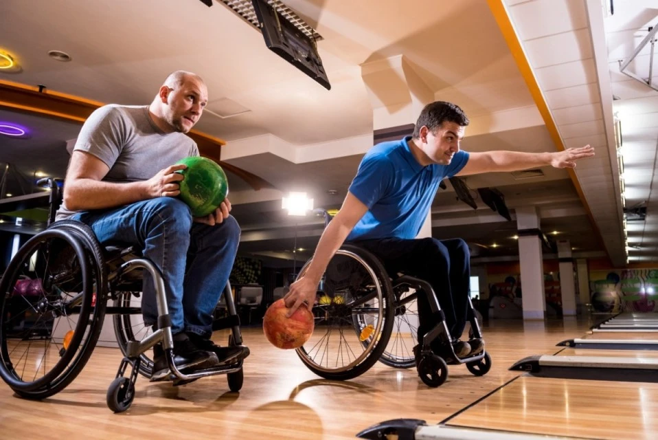 Two friends in wheelchair enjoying a game of ten pin bowling